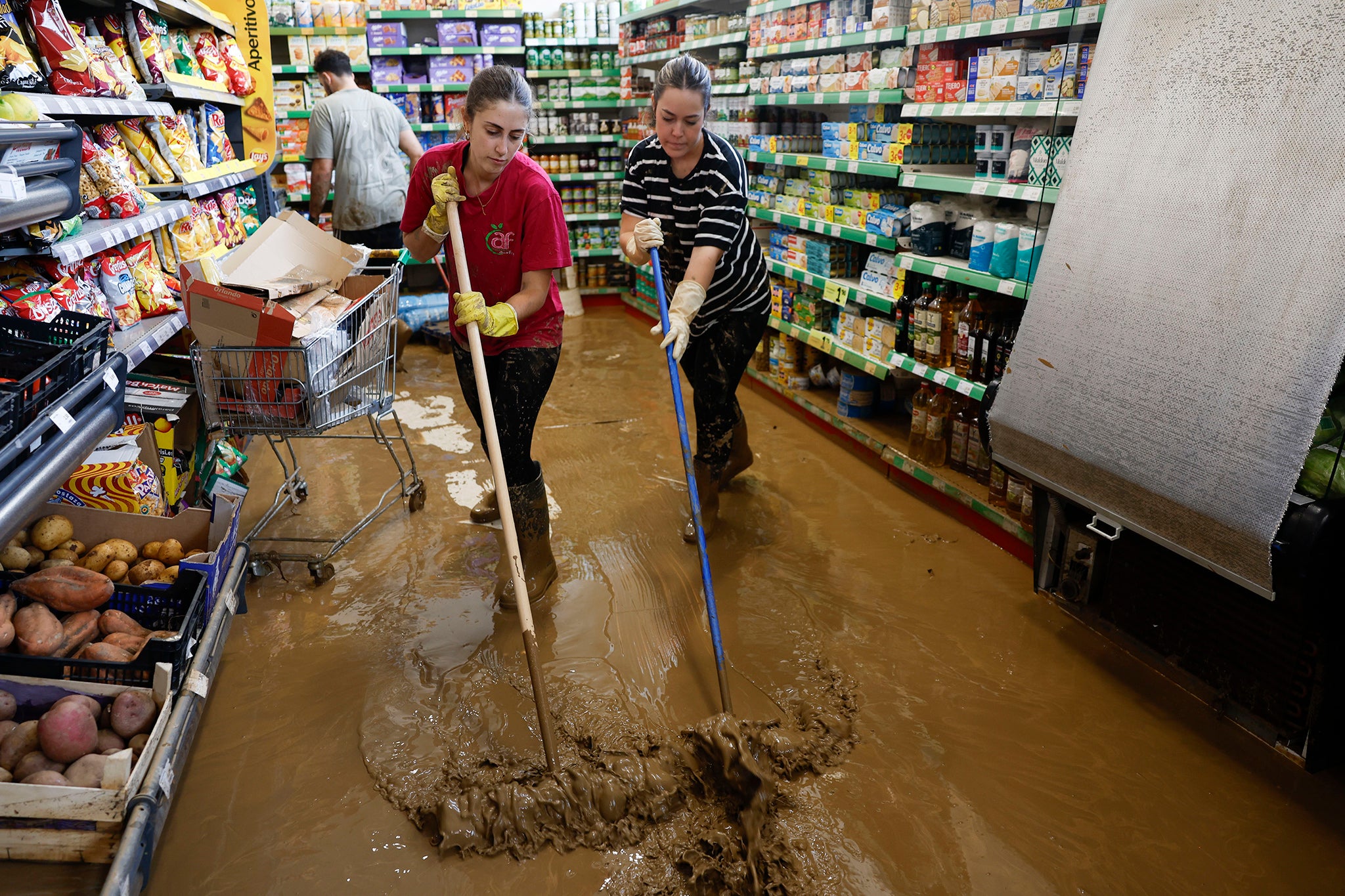 Varias personas limpian un supermercado inundado en España